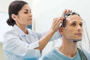 EEG tech applying head gear to a patient