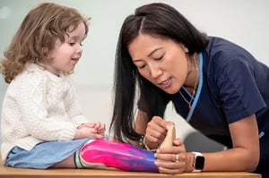 An occupational therapist working with a young girl with a prosthetic leg.