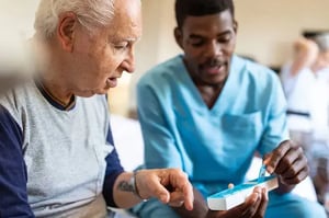 Long Term Care CNA showing an elderly patient a pill box