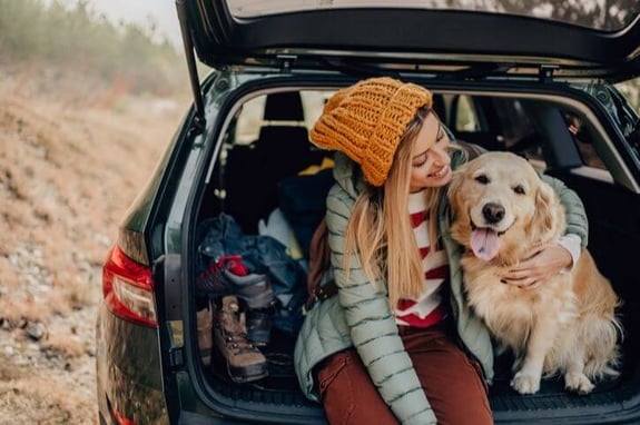 woman and dog in trunk on roadtrip