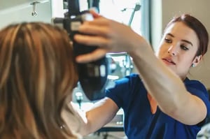 Ophthalmic Technician testing patient eyes with machine