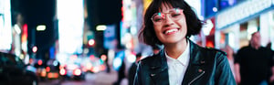 A young woman in the city at night wearing eye glasses