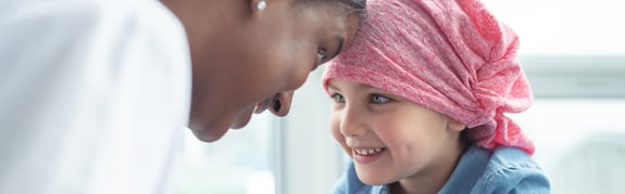 Nurse with a little girl cancer patient smiling