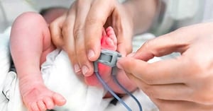 NICU nurse adjusting a foot monitor to a baby's foot