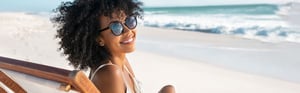 young woman with sunglasses sitting on the beach