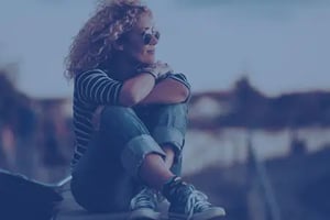 a young woman sitting on a brick wall looing out at the sea